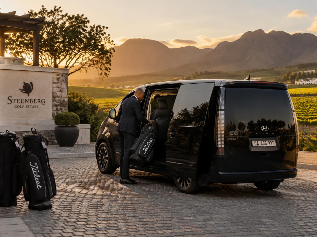 Illustrative black Hyundai Staria with a chauffeur loading golf bags